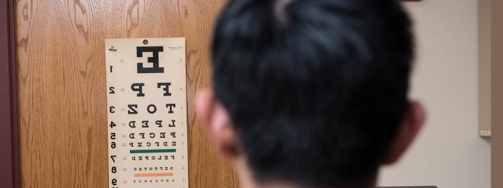 A patient stands in front of the eye exam chart at the clinic.